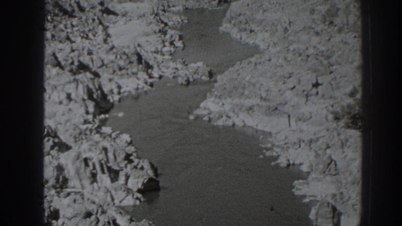 Creek water bordered by rocky terrain and light-colored dirt banks.