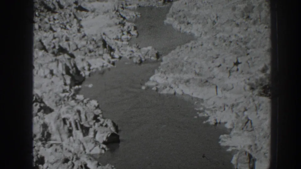 Black-and-white 8mm frame of a creek running through rocky ground in the Oroville, California area, with no people visible.