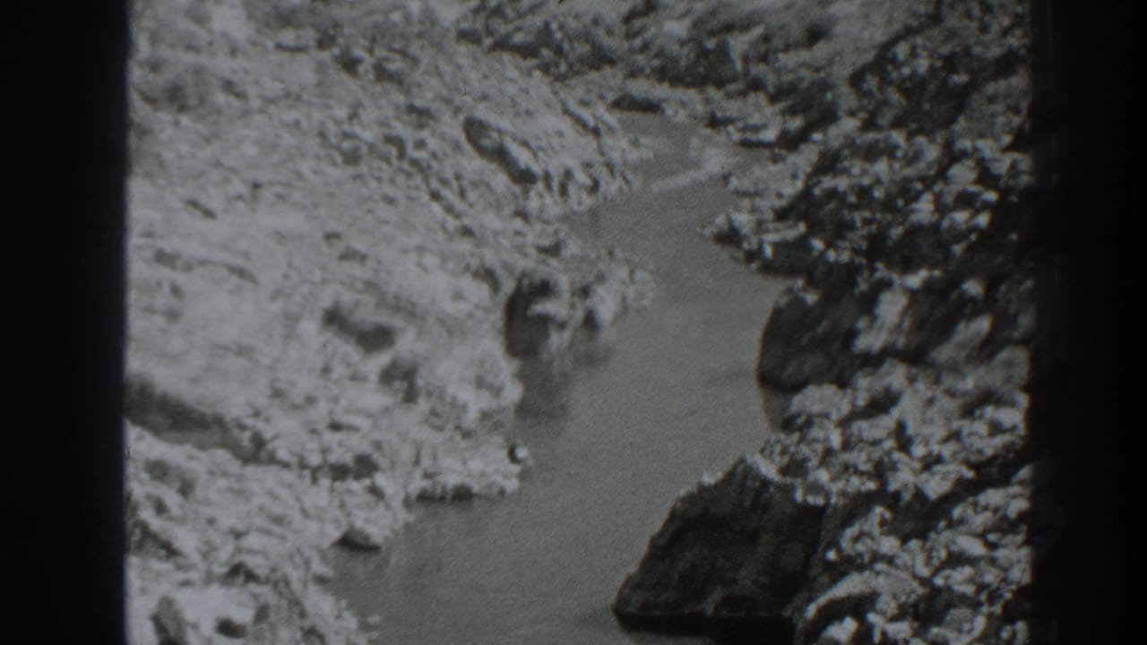 Rocky canyon with a narrow river channel seen in black-and-white 8mm footage.