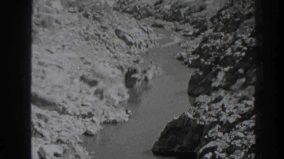 1938 Oroville-area 8mm frame showing a narrow river bordered by pale rock shelves and darker outcrops.