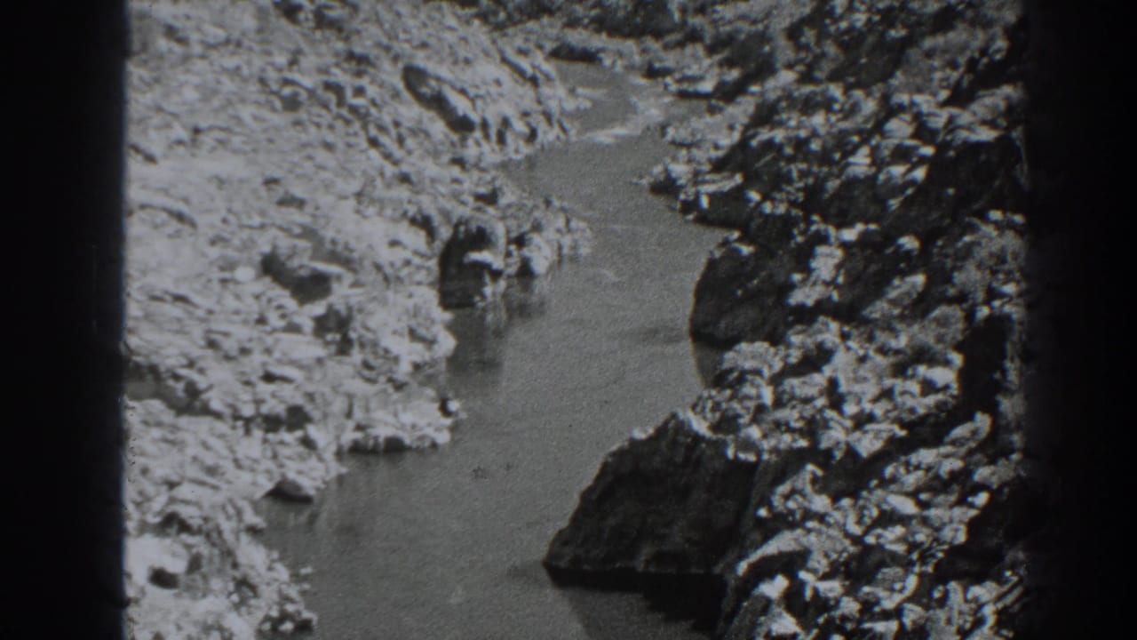 Narrow water channel runs through pale rocky banks with dark film borders.
