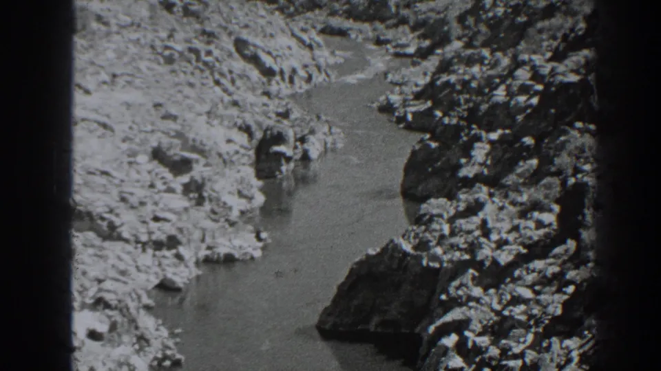 1938 Oroville home-movie frame showing a small stream or river channel between dry, rocky banks in black-and-white 8mm footage.
