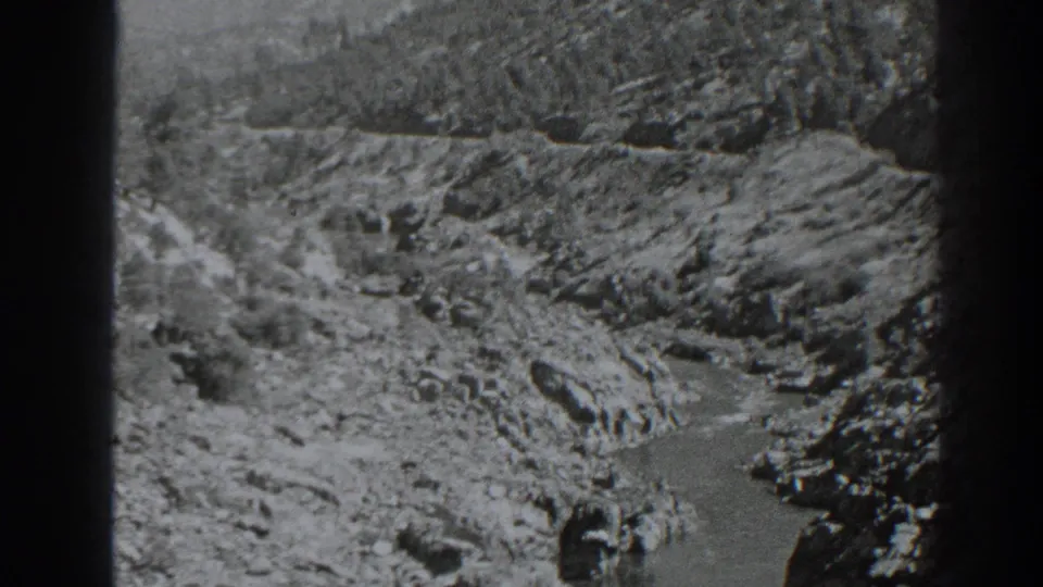 Wider 1938 Oroville landscape frame with eroded rocky slopes, sparse scrub, and a narrow water channel below.