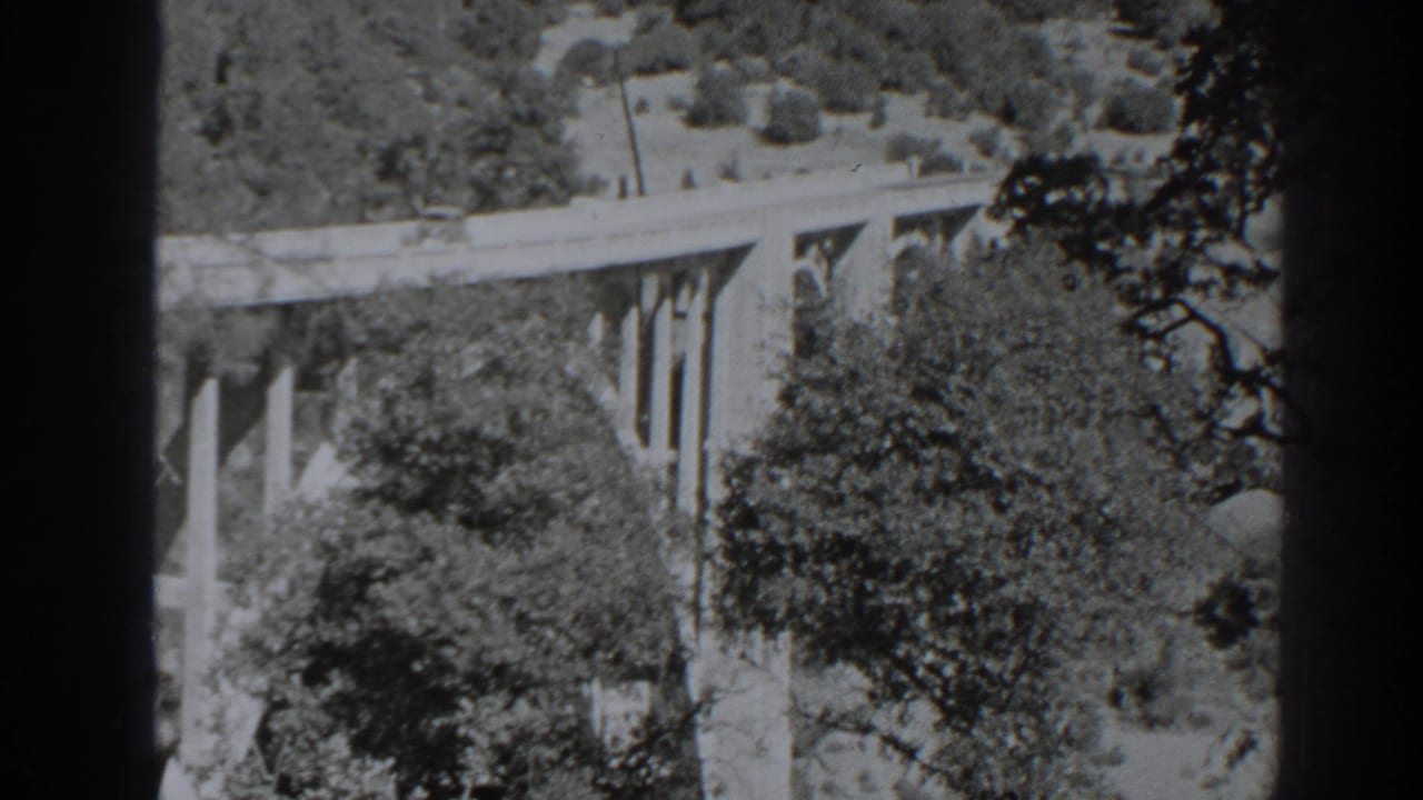 Bridge crossing a wooded hillside with dark film-strip borders visible.