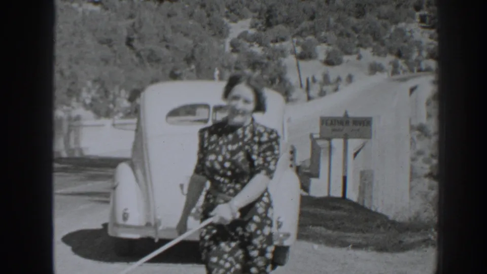 In 1938 Oroville-area home-movie footage, a woman walks a small dog near a parked vintage car and a visible location sign.