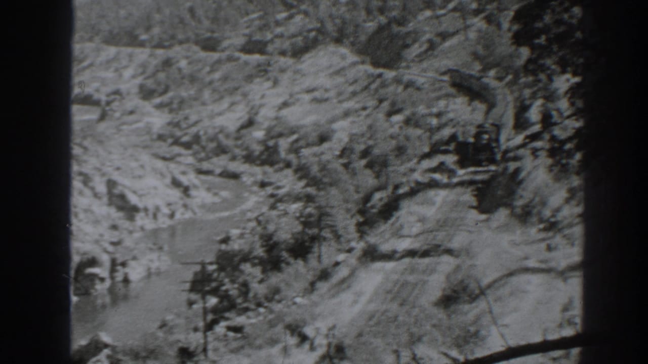 High view of a winding river canyon with tracks and rugged hillsides.