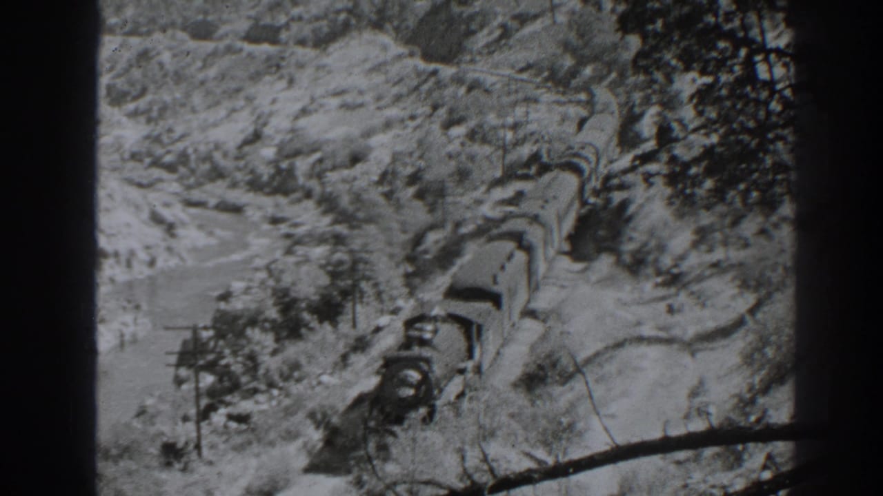 Freight train curves through snow-covered mountain terrain.