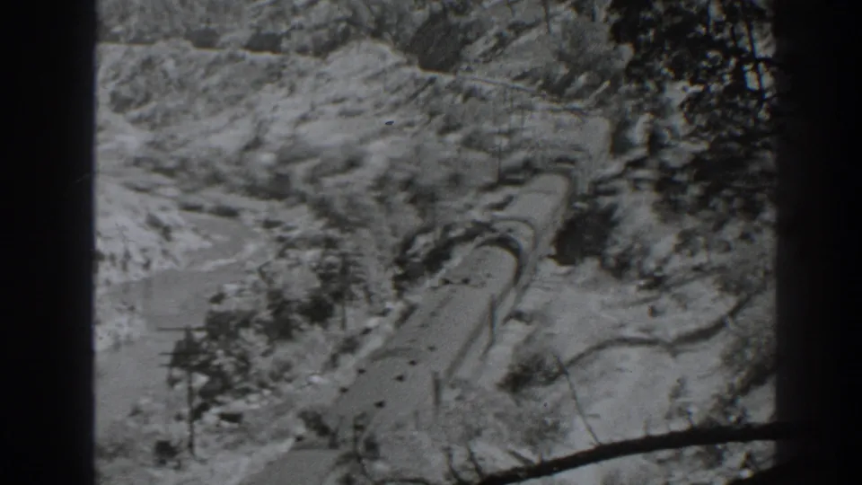 The later frame shows the freight train extending through the snow-covered Oroville pass, with track, trees, and hillside visible.