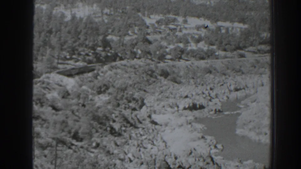 1938 Oroville, California frame of a rocky river landscape with wooded slopes and a rail line, bordered by visible 8mm film edges.