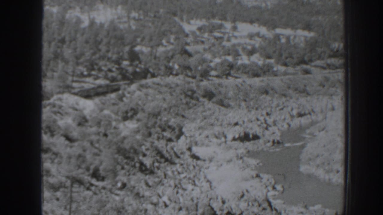Rocky river channel seen from above with wooded hills in the distance.
