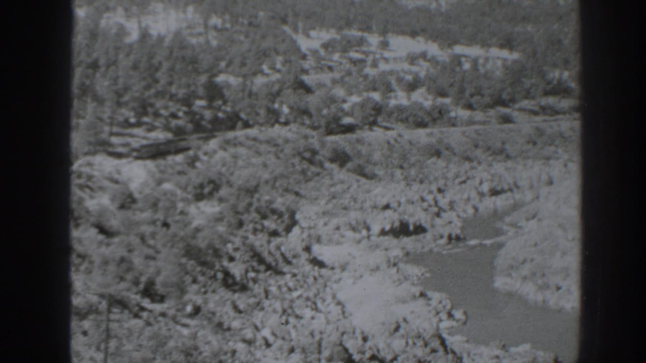 Elevated black-and-white view of rocky terrain and a winding channel.