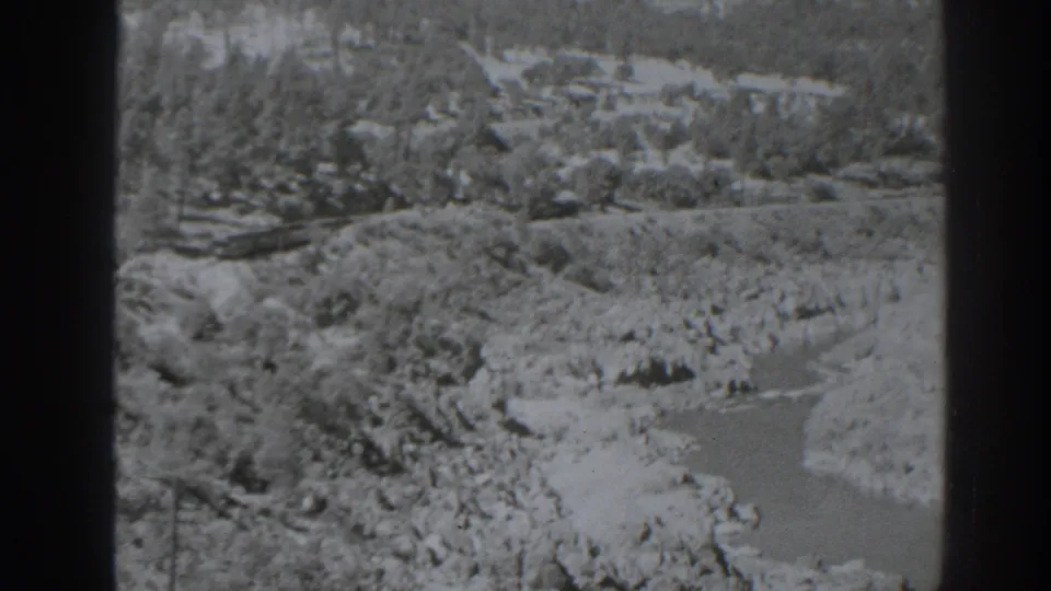 Oroville-area 8mm frame showing a winding rocky channel with brush, trees, and distant hillside detail.