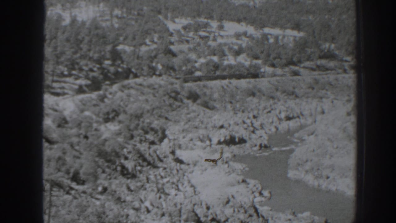 1938 Oroville-area 8mm frame showing a high-angle black-and-white view of a rocky river canyon with trees and exposed banks.