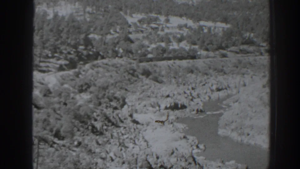 1938 Oroville-area 8mm frame showing a high-angle black-and-white view of a rocky river canyon with trees and exposed banks.