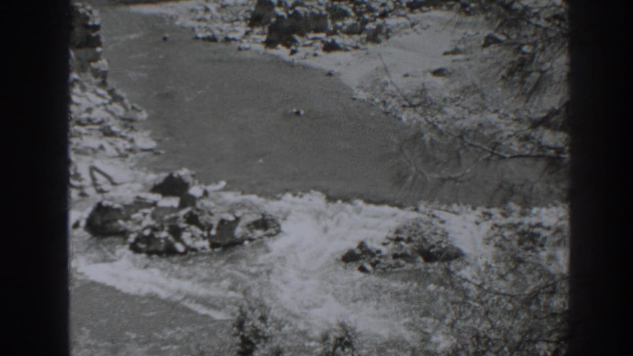 Black-and-white 8mm frame of the Oroville river canyon with turbulent water and exposed rocks.