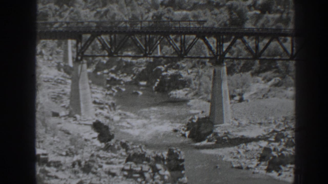 1938 Oroville, California home-movie frame showing a steel railroad bridge spanning fast water and rocks below.