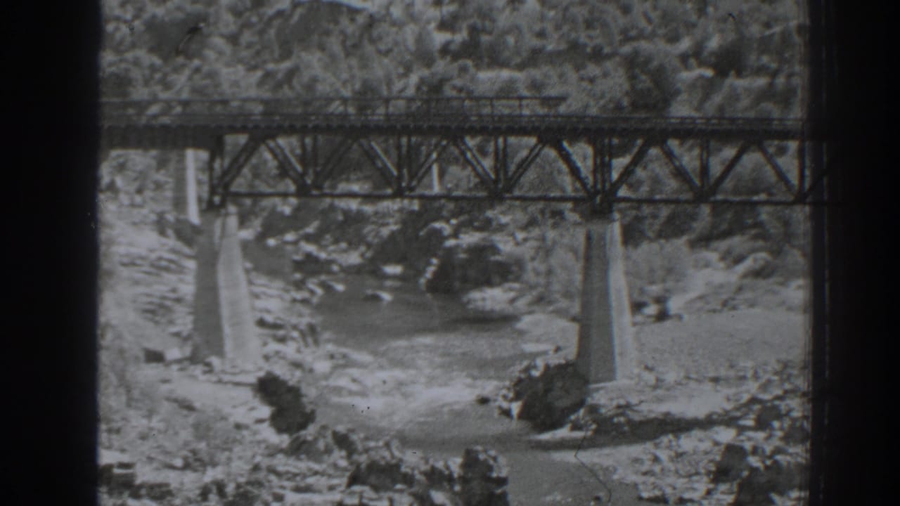 1938 Oroville, California home-movie frame showing a steel truss bridge on concrete piers above a rocky river channel.