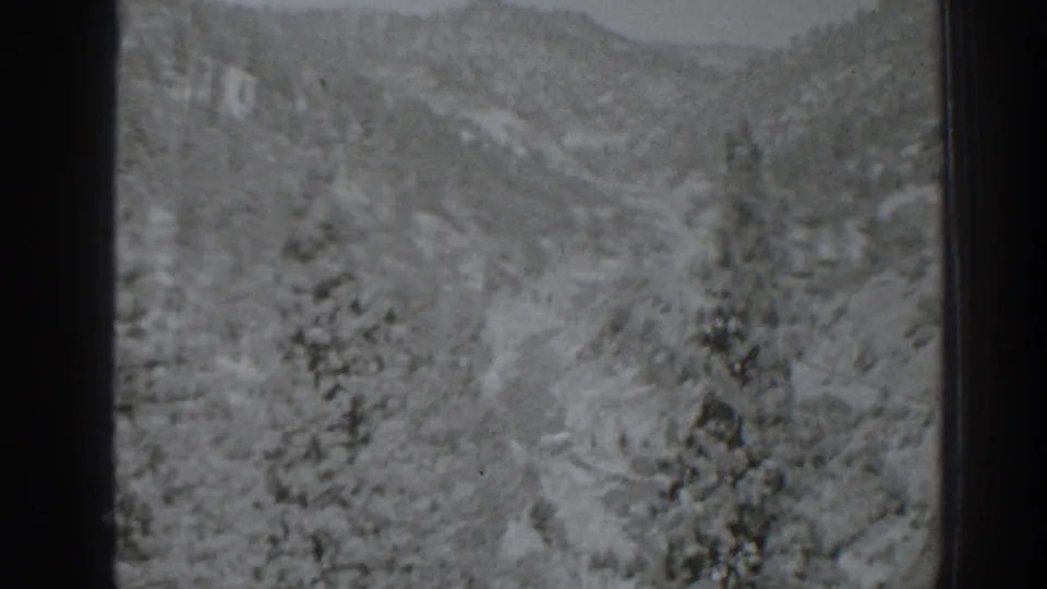 The camera shifts from the bridge toward a soft, distant view of the forested Oroville-area valley and hillside terrain.