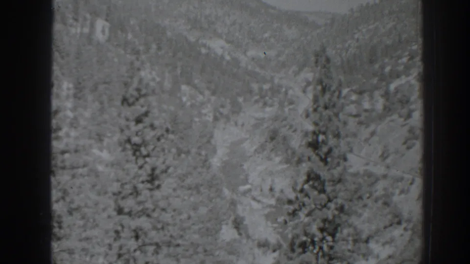 Grainy 1938 8mm frame showing a snowy pine landscape and mountain slope near Oroville, California.