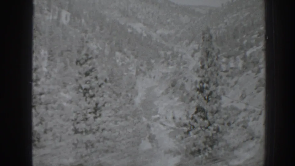 Oroville, California 1938 home-movie frame with snow-bright pines, hazy hills, and visible 8mm texture.