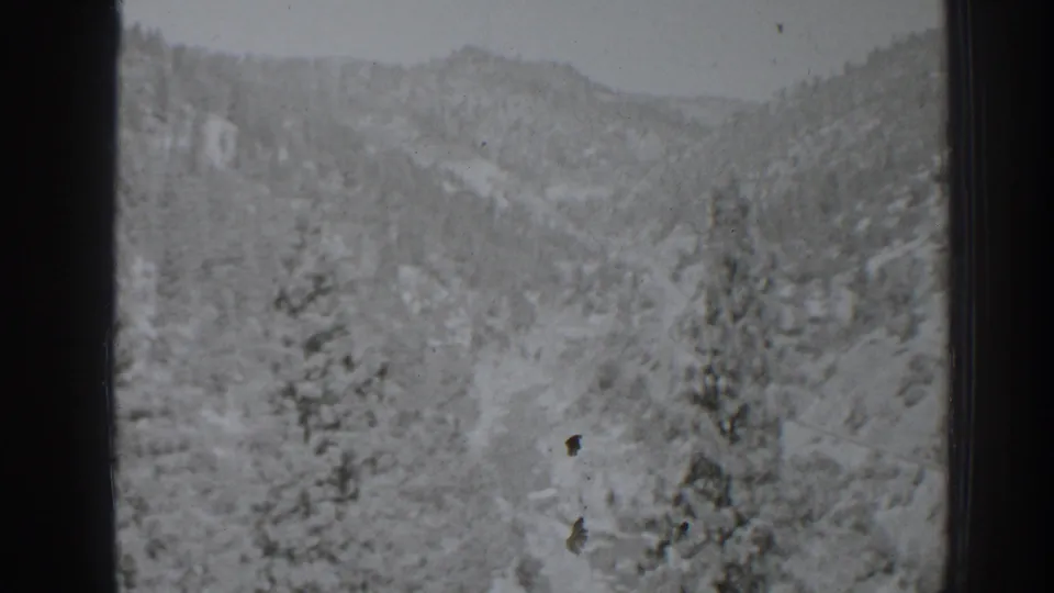 Late-1930s 8mm view near Oroville with a snowy valley, dark pine clusters, distant hills, and visible dust marks.