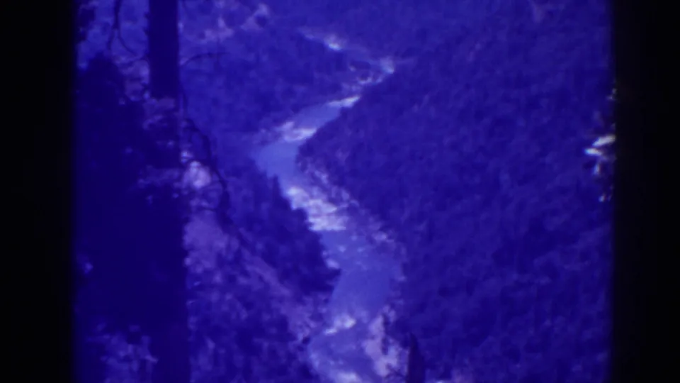 1938 Oroville-area 8mm frame with a pale river bend running through a dense, blue-tinted forest valley.
