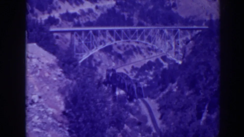1938 Oroville-area 8mm frame showing a steel truss bridge spanning a canyon with slopes and a lower route below.