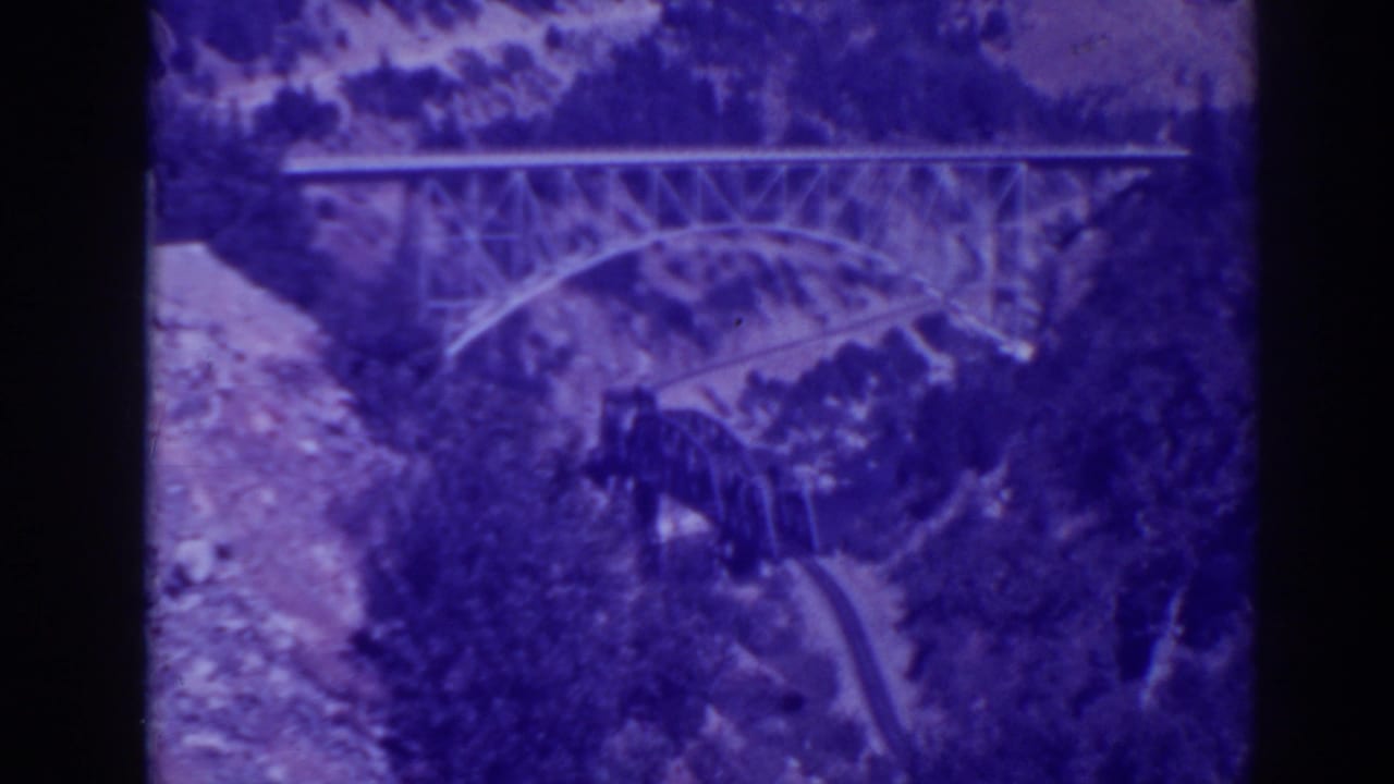 1938 Oroville-area 8mm frame showing steel and arched bridges across Feather River Canyon terrain under cloudy light.