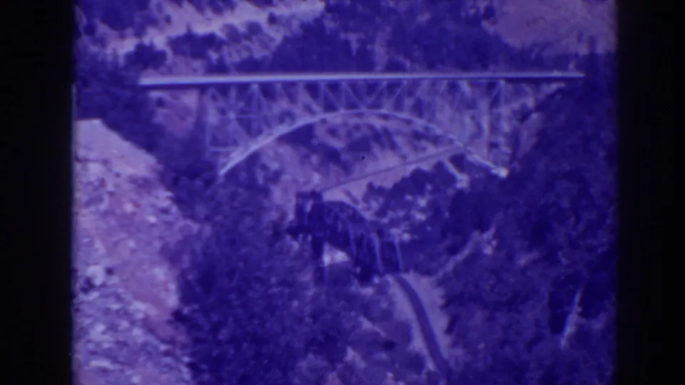 1938 Oroville-area 8mm frame showing steel and arched bridges across Feather River Canyon terrain under cloudy light.