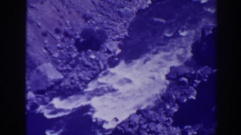 1938 Oroville home-movie frame showing foamy creek water moving between dark rocks and stones.