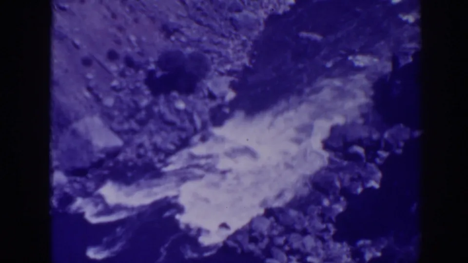 1938 Oroville frame showing a rocky creek current, white foam, and dark stream edges in tinted 8mm film.