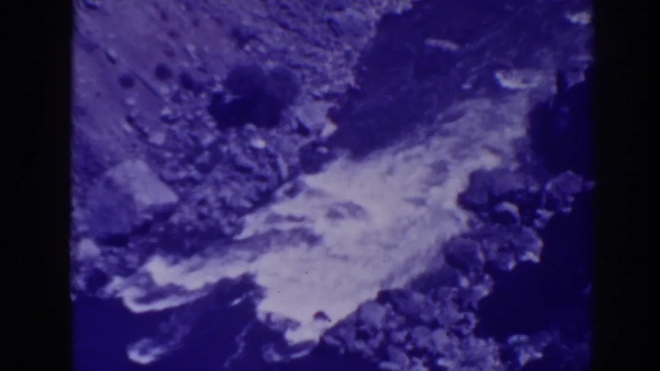 1938 Oroville-area home-movie frame showing rugged rock terrain and a pale strip that may be water or roadside surface.