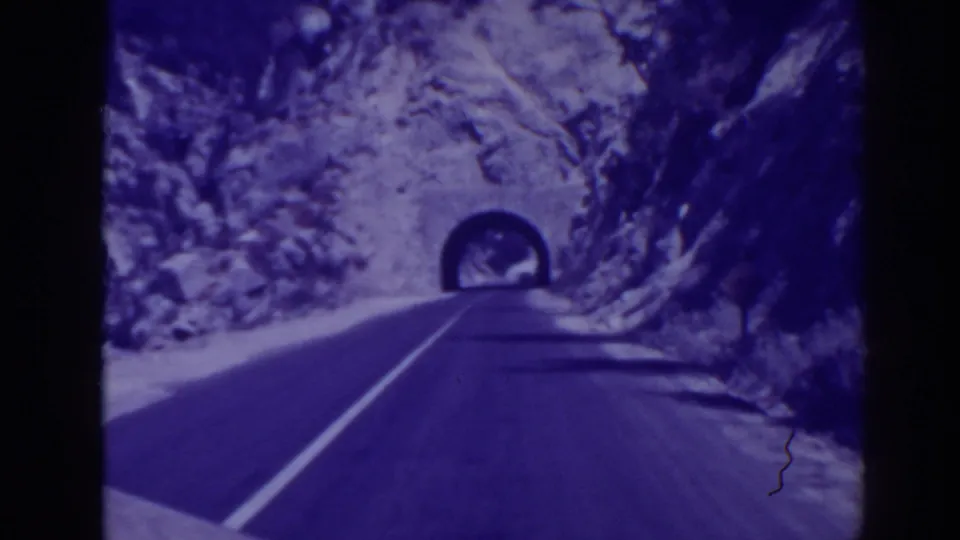 1938 Oroville, California road view approaching a dark tunnel entrance through rugged rock walls.