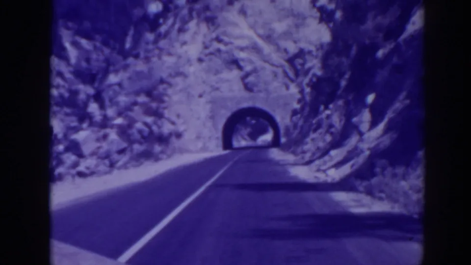 Vehicle-perspective 8mm frame from 1938 showing a mountain road nearing a tunnel in Oroville, California.