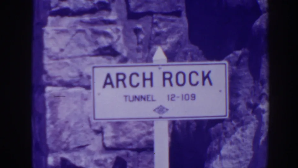 The Arch Rock Tunnel sign marked 12-109 stands in front of a rocky stone wall in the Oroville clip.