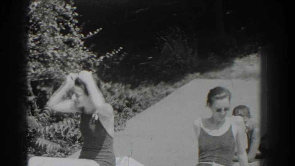 At a 1937 Southampton pool, one woman adjusts her hair while another sits near a child at the pool edge.