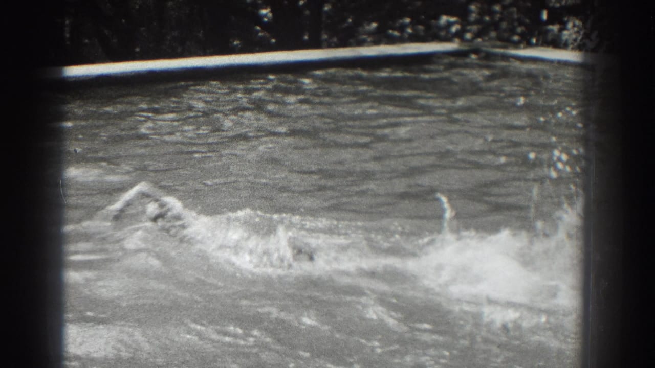 Partly submerged swimmer moving through a pool with splashing water.