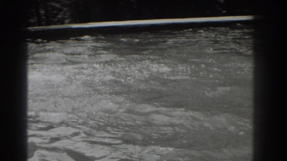 Black-and-white 8mm frame showing disturbed pool water and fading splash marks in the Southampton swimming scene.
