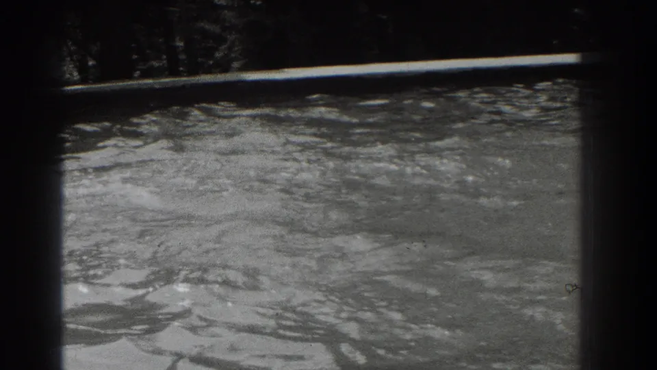 1937 Southampton, New York 8mm frame showing rippling river water, a shadowed tree line, and visible film borders.