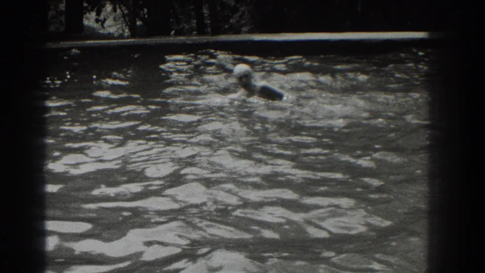 Black-and-white 1937 8mm frame showing a swimmer gliding through an outdoor pool in Southampton, New York.