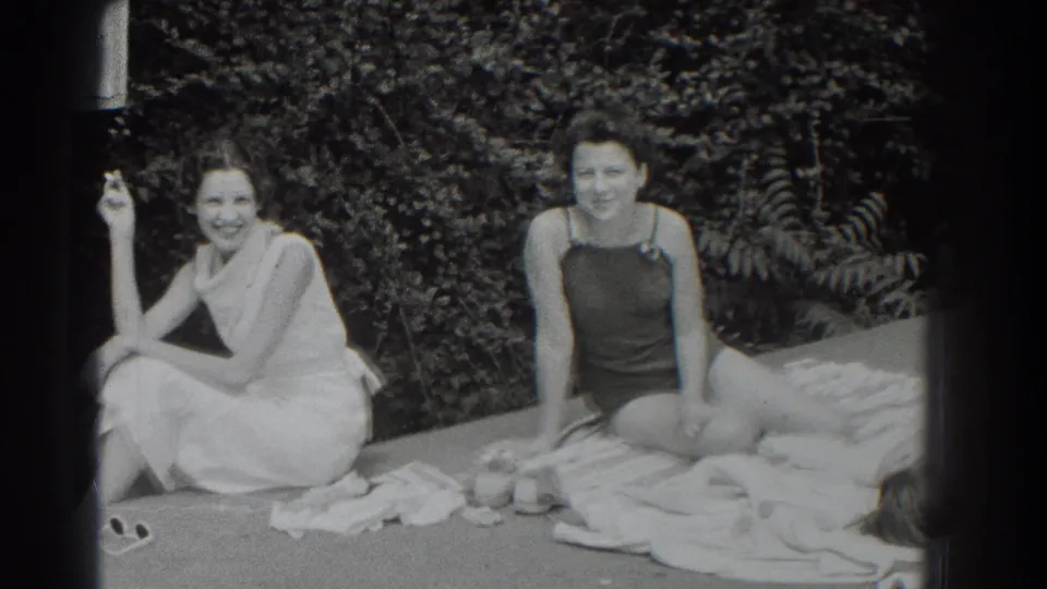 Two women in Southampton, New York, sit outdoors in 1937, one in a light dress with a cigarette and one in a dark bathing suit.