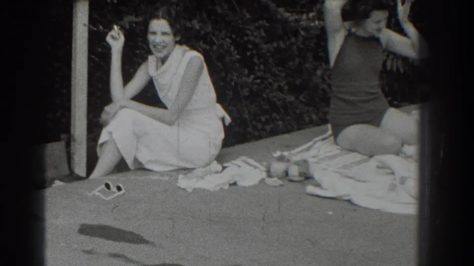 1937 Southampton frame of a smiling woman in a light dress holding a cigarette beside a woman in a dark swimsuit.