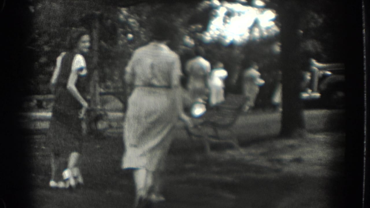 1937 Southampton, New York frame with women moving through a shaded park and a 1930s-style automobile partly visible at the edge.