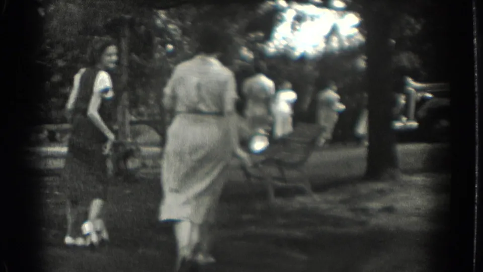 1937 Southampton, New York frame with women moving through a shaded park and a 1930s-style automobile partly visible at the edge.