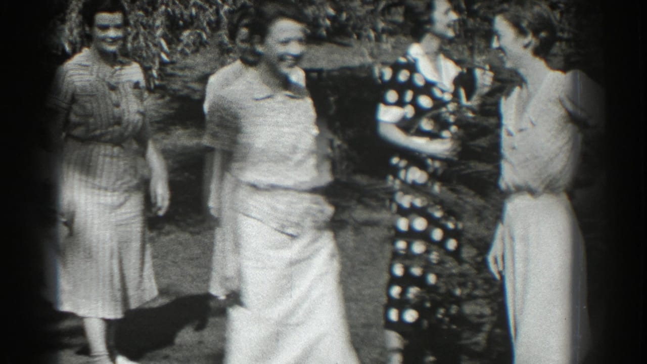 Four women stand together outdoors, smiling and talking in dresses.