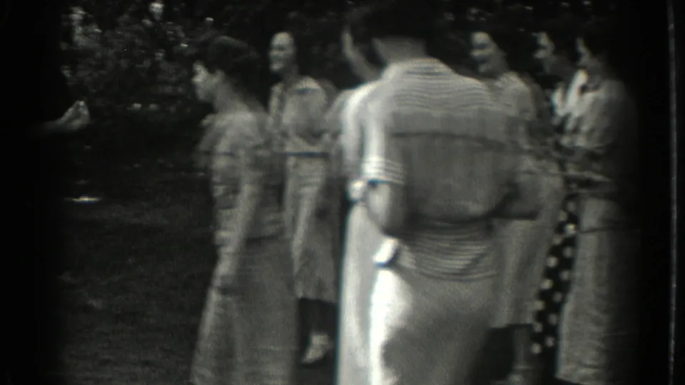A handheld 1937 Southampton park view shows women standing together, partly obscured by a figure in a striped knit top.