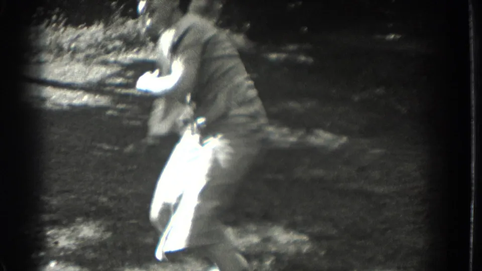1937 Southampton home-movie frame showing a woman in a dress dancing on grass in bright sun, with another figure partly visible.