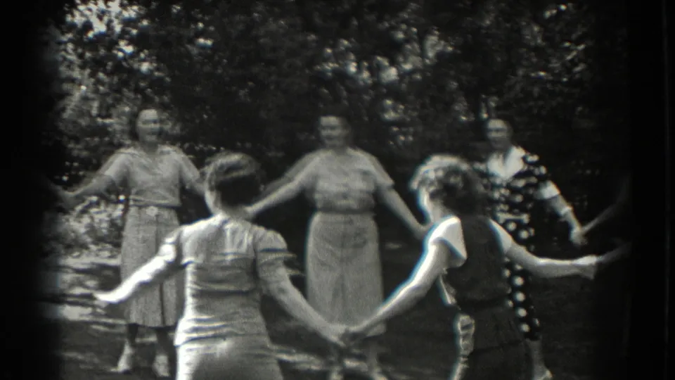 Several women form a loose hand-held circle in a leafy Southampton backyard, consistent with 1937 home-movie footage.