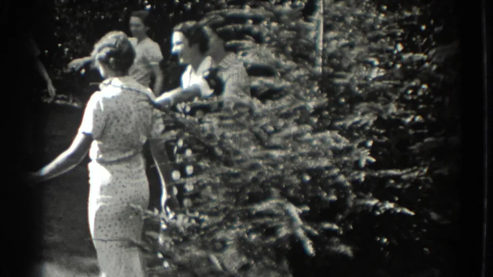 In the Southampton 1937 home-movie scene, a young participant in a light outfit faces others during the circle game.