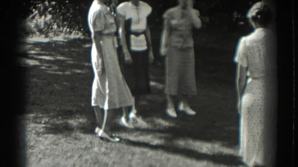 The handheld 8mm frame catches women in dresses on a Southhampton lawn as the circle shifts near the end of the clip.